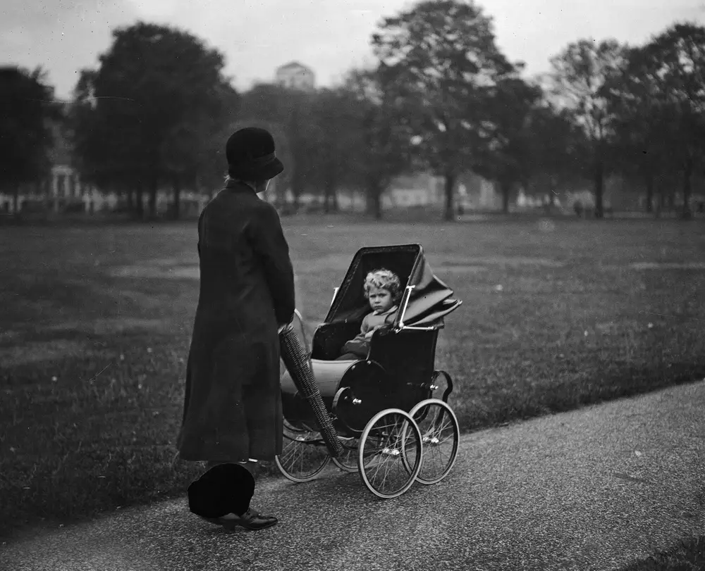 พ.ศ. 2472/ค.ศ. 1929: พระพี่เลี้ยงกำลังเข็นรถเข็นเด็กซึ่งมี "เจ้าหญิงเอลิซาเบธที่ 2" ทรงนั่งเล่นอยู่ในกรีนปาร์ค (Green Park)